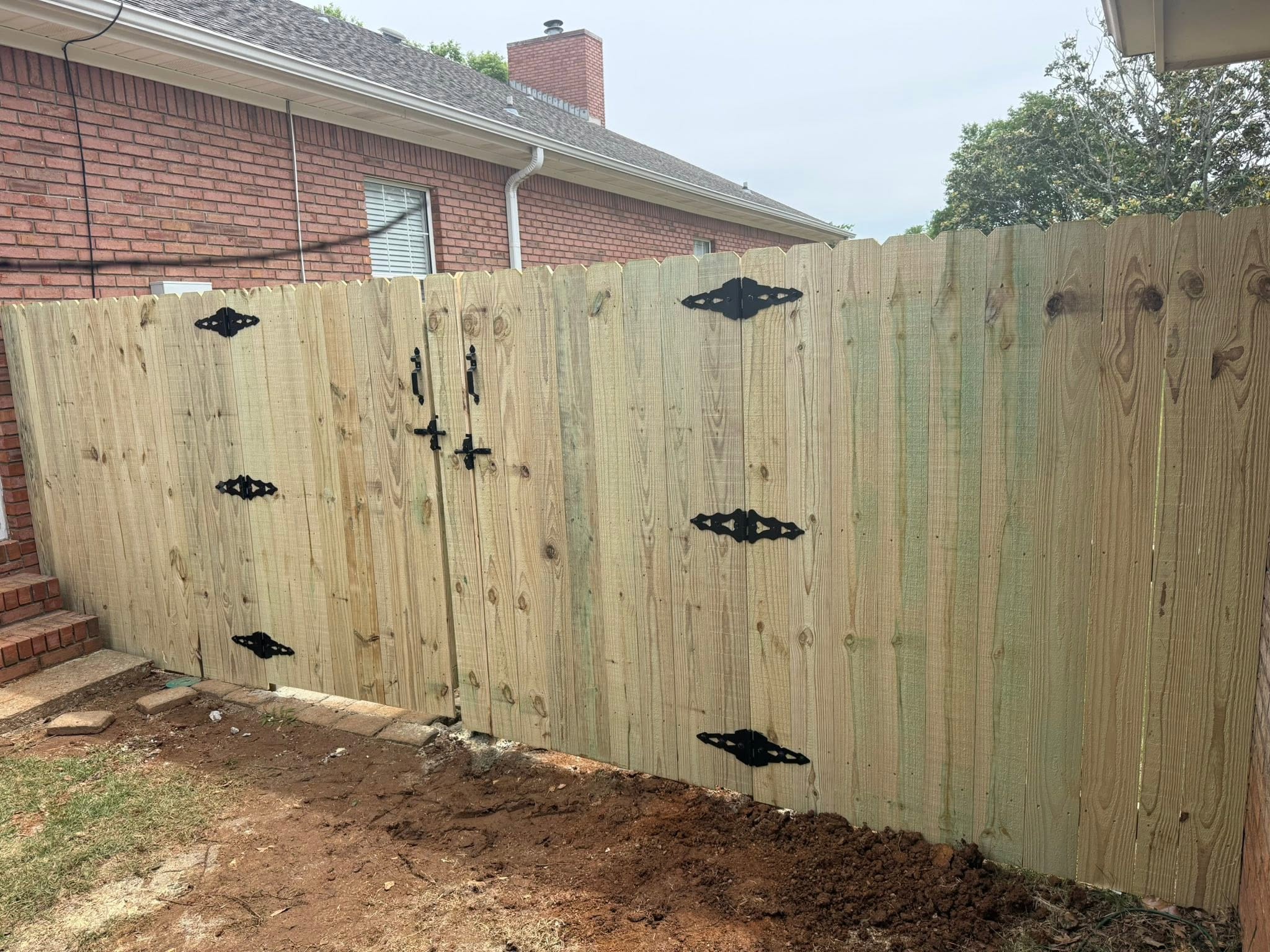 Wood privacy fence double gate with decorative black hinges in Colbert County, AL Wood privacy fence double gate with decorative black hinges in Colbert County, AL