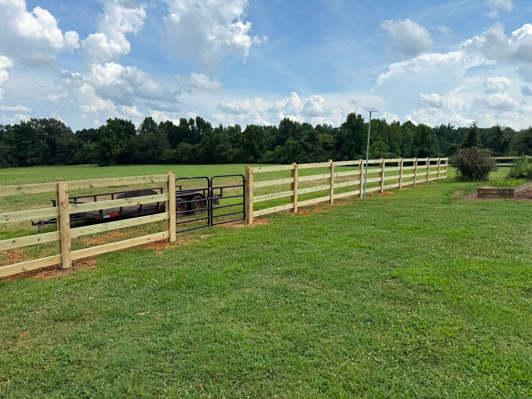 Four-rail wood ranch fence with black metal gate in Northern Alabama Four-rail wood ranch fence with black metal gate in Northern Alabama