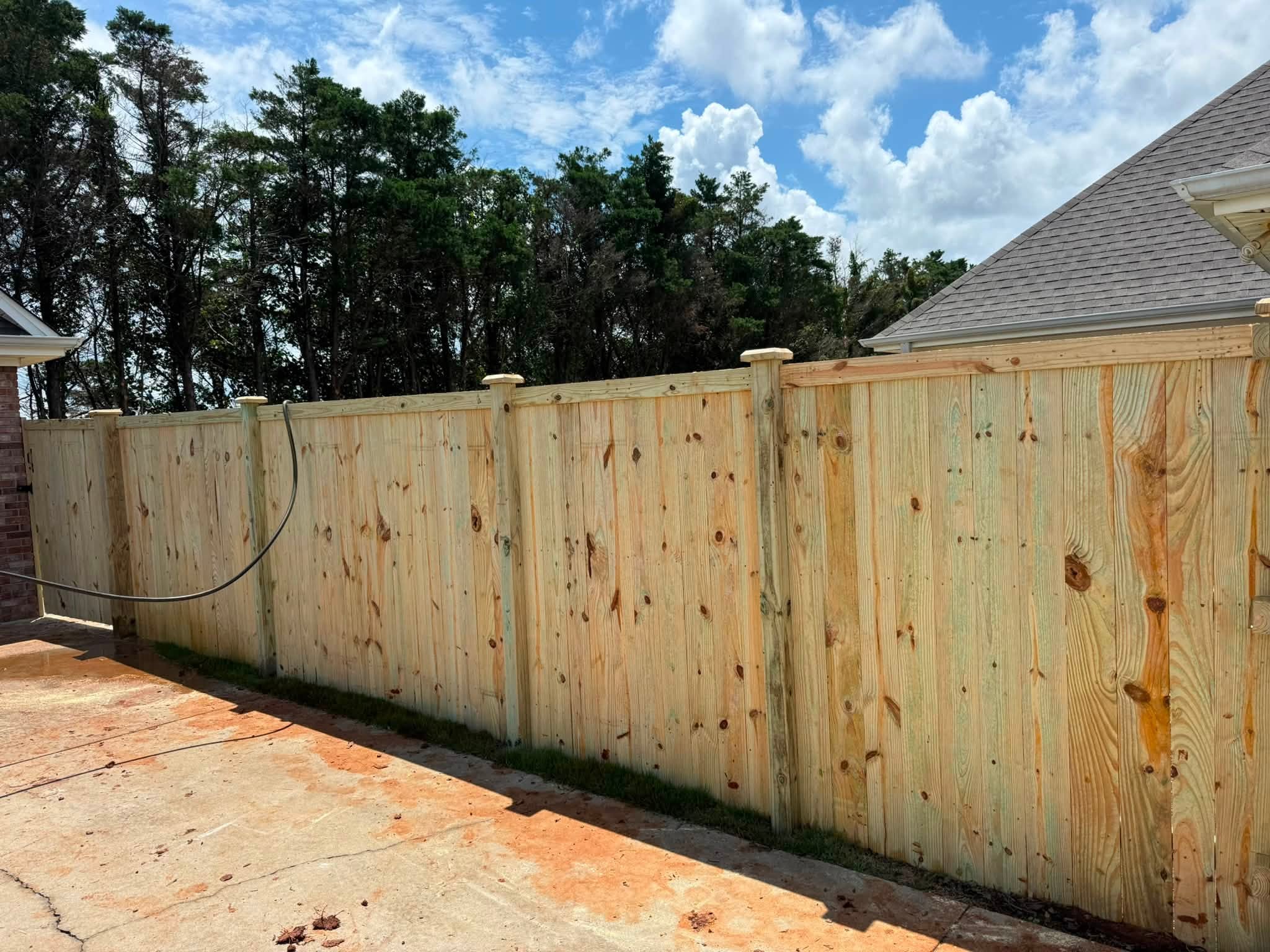 Fresh wood privacy fence installation along a driveway in Muscle Shoals, AL Fresh wood privacy fence installation along a driveway in Muscle Shoals, AL