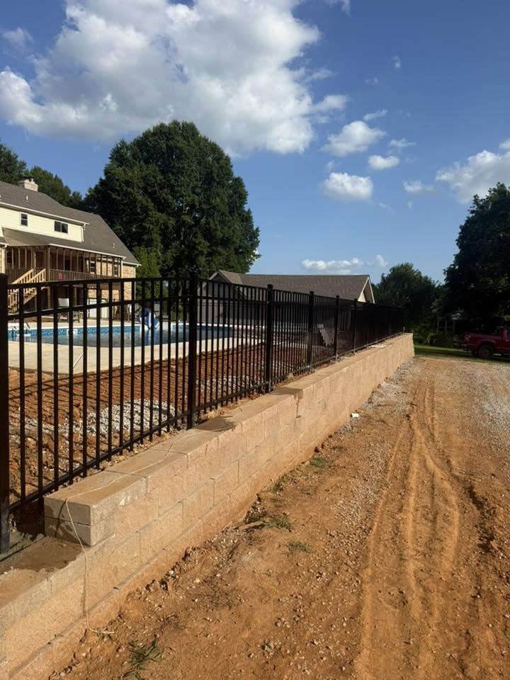 Black metal fence on concrete retaining wall near a pool in Muscle Shoals, AL Black metal fence on concrete retaining wall near a pool in Muscle Shoals, AL